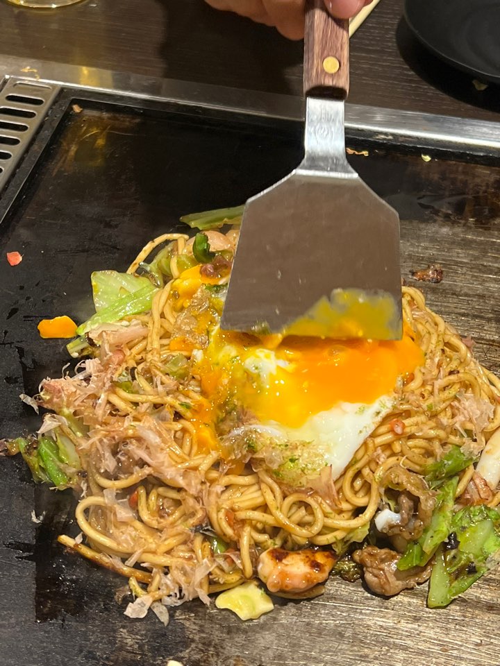 야키소바 위에 반숙 달걀을 올리는 모습