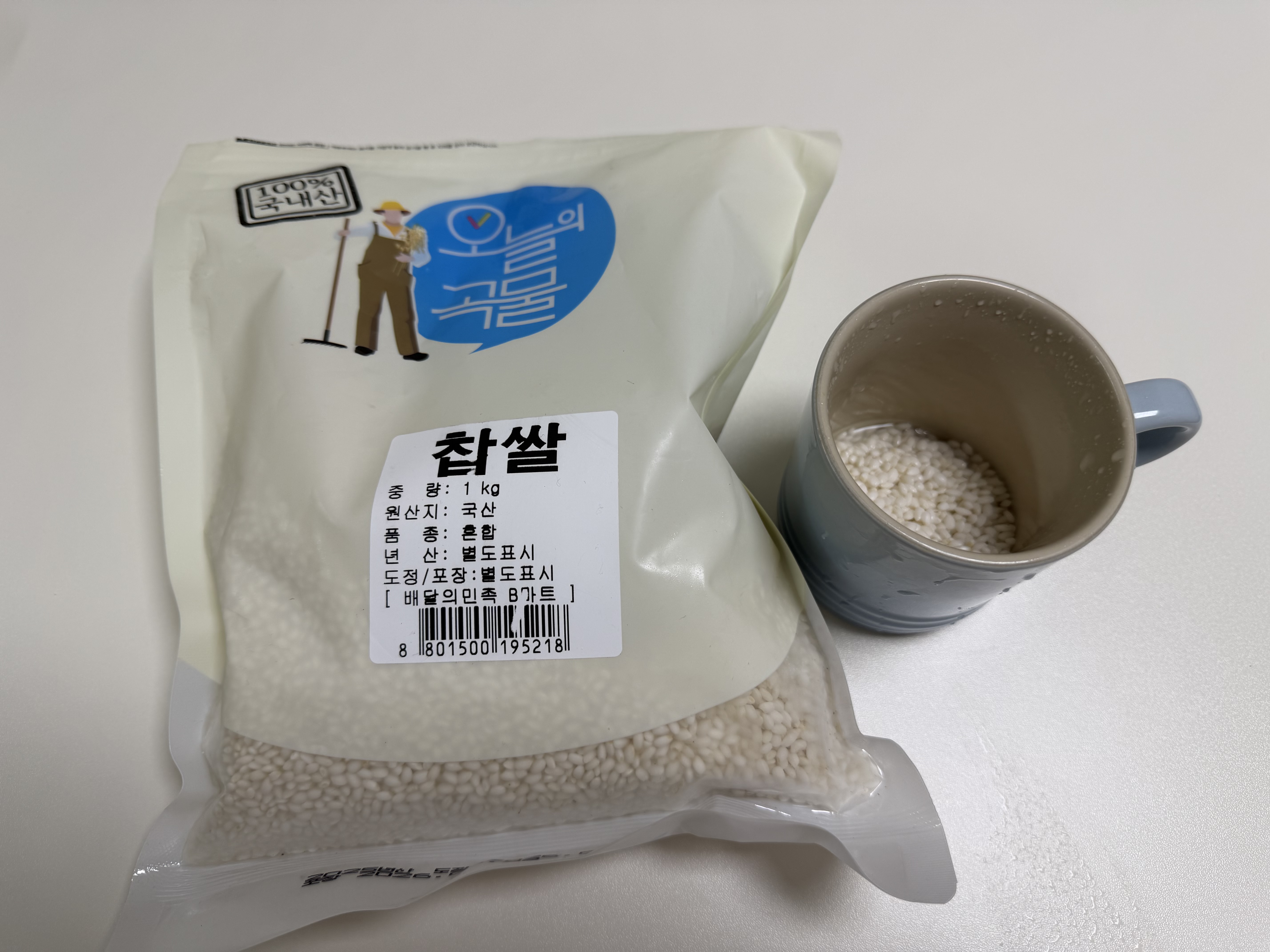찹쌀 찹쌀 봉지와 계량컵에 담긴 찹쌀, 1kg 봉지 옆에 회색 머그컵에 찹쌀이 담겨 있다